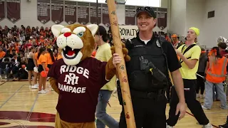 school officer and mascot hold spirit stick