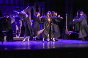 actors doing a dance with broomsticks