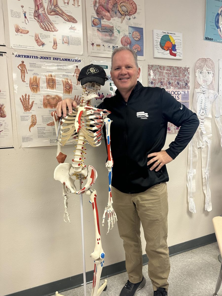 teacher poses next to skeleton