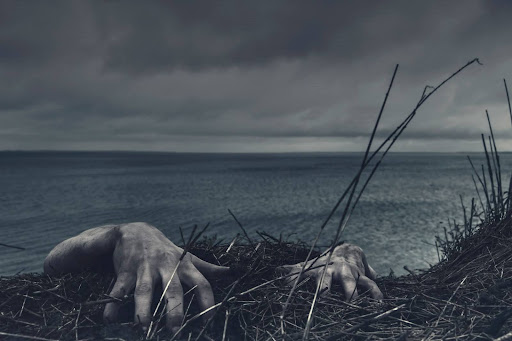 Zombie hands emerge by an ocean
